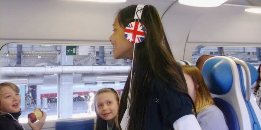 Ragazza in treno con cuffie bandiera inglese